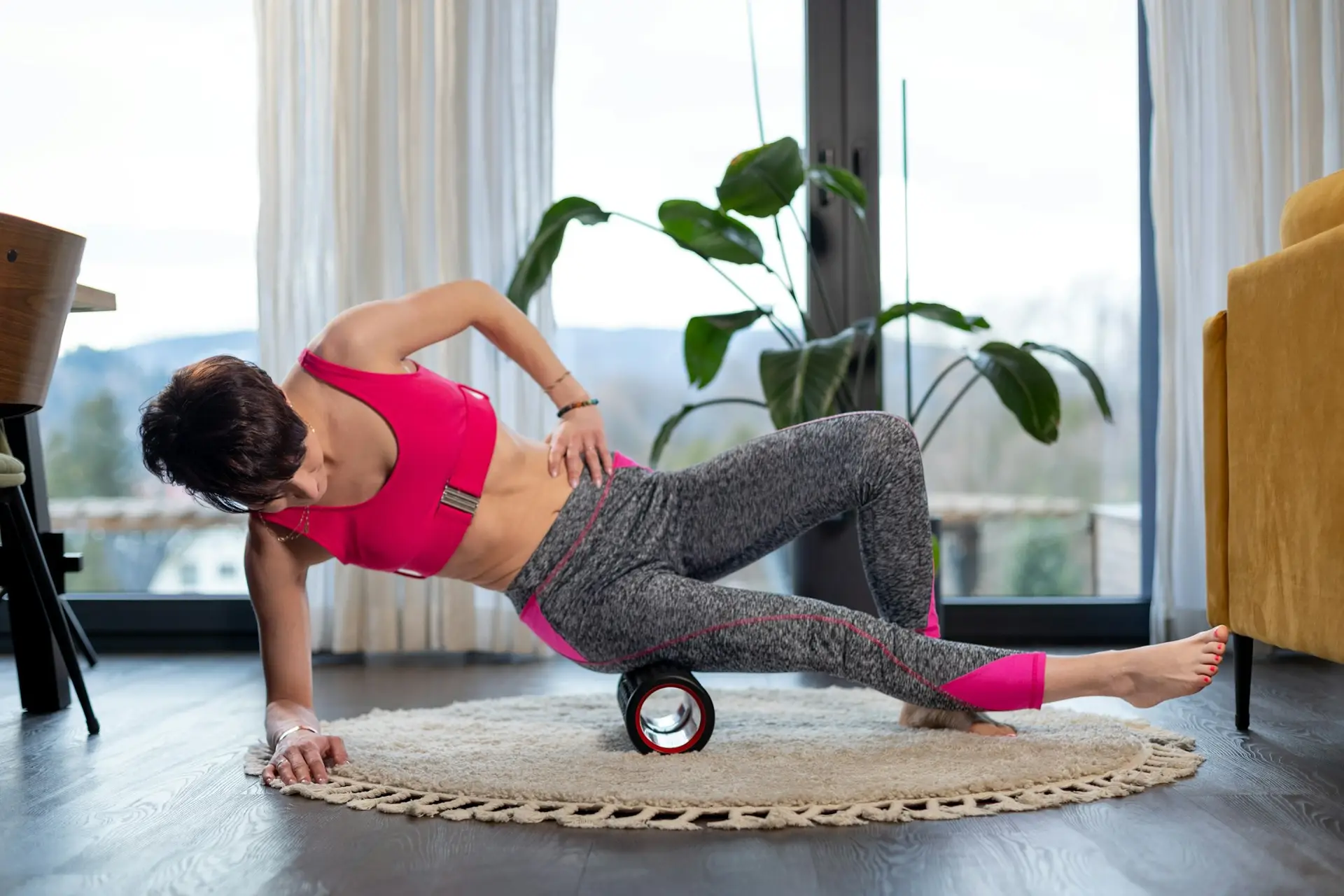 Sporty woman doing exercise and massage using roller at home