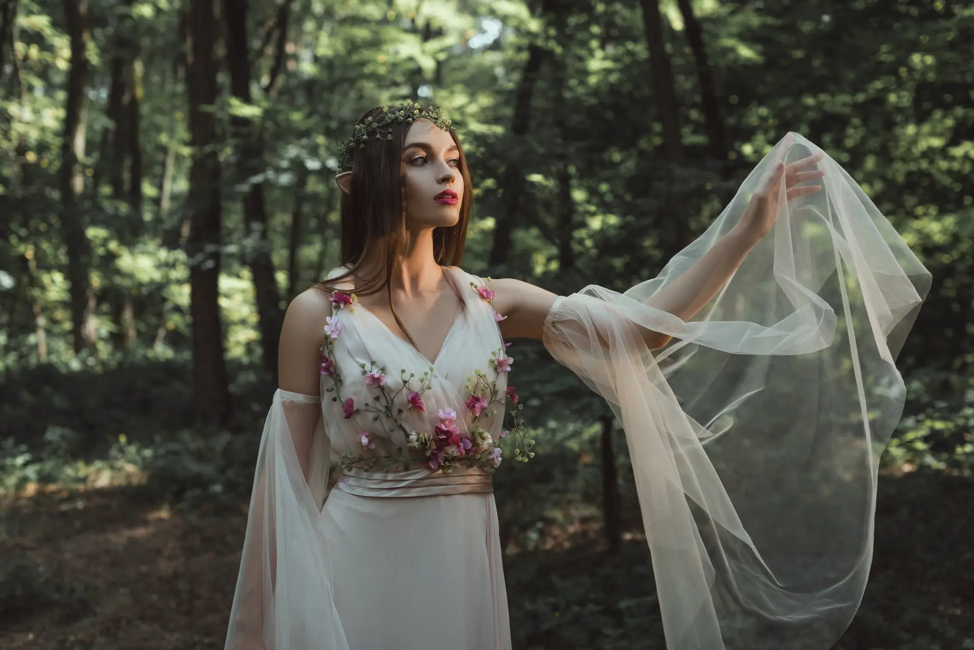 mystic elf in elegant dress with flowers in forest